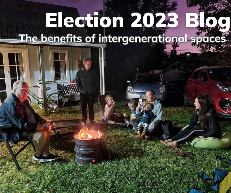 This postcard has an image of 7 people around a campfire at dusk. It is a joyful scene featuring at least three different generations. The words say: Election Blog 2023 - the benefits of intergenerational spaces.